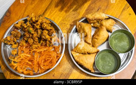 Traditionelle indische Snacks Samosa, Pakode und Jalebi mit grünem Chutney im Innenbereich Stockfoto