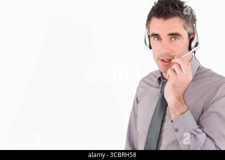 Mann in seinen 30ern, der Anrufe im Büro entgegennimmt, mit Krawatte und Headset, Kopierraum Stockfoto
