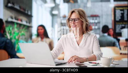 Senior Woman Hält Coffee Cup Und Trifft Sich Virtuell Mit Business Tutor Stockfoto