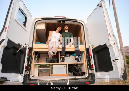 Paare, die sich in einem umgebauten Van entspannen und das Leben im Wohnmobil genießen Stockfoto