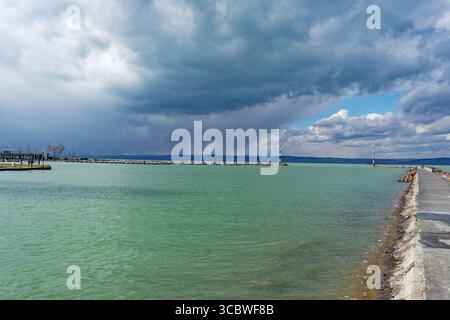 Eine wunderschöne Wasserlandschaft mit einem dramatischen Himmel über einem See mit Leuchttürmen und einem Pier. Stockfoto
