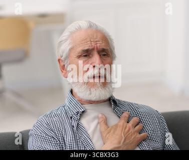 Ein älterer Mann, der zu Hause an Brustschmerzen leidet Stockfoto