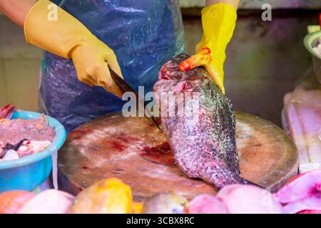 Man schneidet und bereitet frischen Fisch für den Verkauf mit einem Spalter auf dem Markt vor. Stockfoto