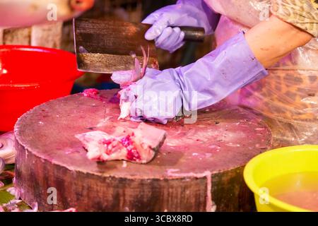 Man schneidet und bereitet frischen Fisch für den Verkauf mit einem Spalter auf dem Markt vor. Stockfoto