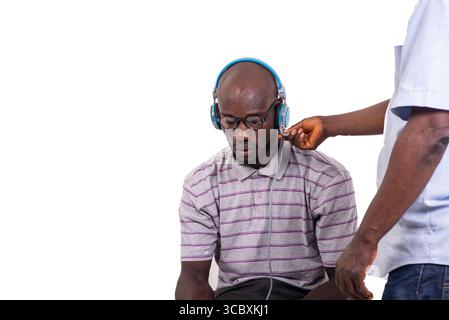 Junger Mann, der auf einem Stuhl sitzt und ein Telefon-Headset trägt. Stockfoto