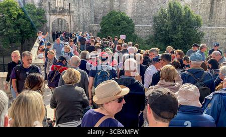 Dubrovnik, Kroatien. August 2025. Eine Menge Touristen versammelt sich am Eingang der befestigten alten Stadtmauern von Dubrovnik. Im Vordergrund rastet eine Frau überrascht vor der langen Warteschlange. Seit 2017 hat Kroatiens berühmteste Stadt, die auch für ihren Ruf als „überfüllte Stadt der Welt“ bekannt ist, zahlreiche Maßnahmen zur Bewältigung des Touristenzustroms umgesetzt, einschließlich Bemühungen, Besucherströme zu organisieren, indem Besucherplätze für die wichtigsten Arten von Tourismus erschüttert werden: Kreuzfahrtpassagiere, Reisebusgruppen und Touristen, die in den Unterkünften der Stadt wohnen Stockfoto