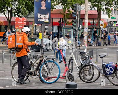 Ein Lieferando Fahrradkurier beginnt am 31. Juli 2025 in der Nähe einer Bushaltestelle in Bonn, Nordrhein-Westfalen. Stockfoto
