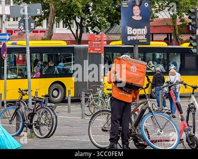 Ein Lieferando Fahrradkurier beginnt am 31. Juli 2025 in der Nähe einer Bushaltestelle in Bonn, Nordrhein-Westfalen. Stockfoto