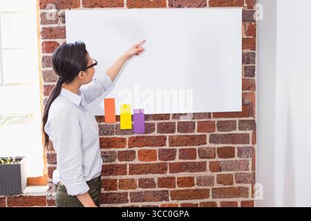 Der Moderator steht neben einem Poster auf einer Ziegelwand, die nach oben rechts zeigt, farbige Streifen, Fensterblöcke Stockfoto