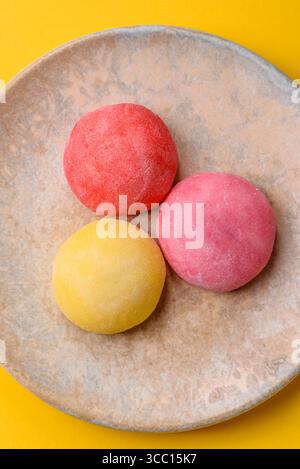 Japanische Mochi, Eis oder asiatische Süßigkeiten aus Reismehl mit Fruchtfüllung. Mochi verschiedener Farben mit Fruchtfüllung als Lebensmittelhintergrund Stockfoto