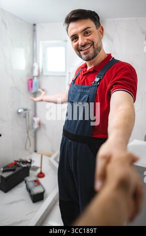 Klempner schüttelt dem Kunden nach Abschluss der Arbeiten im Badezimmer die Hand Stockfoto