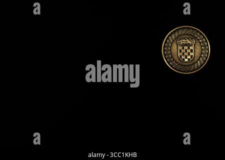 Eine detaillierte Nahaufnahme einer Goldmünze mit einem aufwendigen historischen Emblem auf dunklem Hintergrund, die einen markanten und eleganten Kontrast schafft. Stockfoto