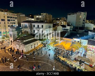 Nächtlicher Blick auf den Monastiraki-Platz in Athen, Griechenland, mit einer alten Kirche, beleuchteten Straßen und Spaziergängen. Stockfoto