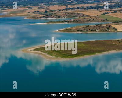 Ruhiger Blick aus der Vogelperspektive auf den Polyfytos-See in Griechenland, umgeben von üppigen Hügeln und ruhigem, blauem Wasser. Eine ruhige Naturlandschaft, perfekt für Reisen und nat Stockfoto