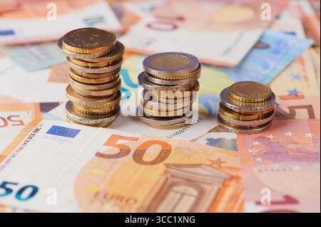 Auf einer Tabelle befinden sich Stapel von Münzen und Euro-Banknoten, die das Finanzwachstum darstellen Stockfoto