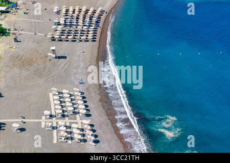 Blick aus der Vogelperspektive auf den Strand von Agia Anna in Evia, Griechenland. Strohschirme, Sonnenliegen, Kieselstrand und kristallklares Wasser sorgen für einen erholsamen Sommerurlaub. Stockfoto