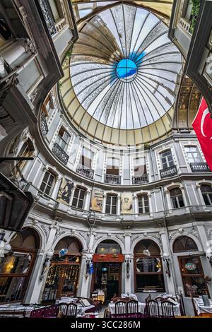 Istanbul, Türkei - 11. November 2023: Verziertes Inneres des historischen, von Cicek Pasaji überdachten Passageways mit Restaurants und Geschäften unter dem Glasdach Stockfoto
