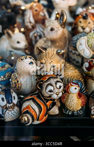 Farbenfrohe Tierfiguren aus Keramik sind hinter Glas in einem Schaufensterfenster ausgestellt. Sammlermarkt, Nostalgie-Design, Gedächtnismarketing Stockfoto