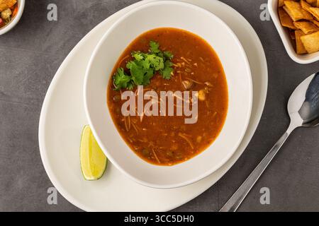Scharfe mexikanische Hühnersuppe mit Nudeln, garniert mit frischem Koriander und Limettenkeil Stockfoto