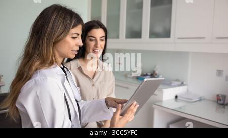 Positive junge hispanische Ärztin erklärt Untersuchungsbericht Stockfoto