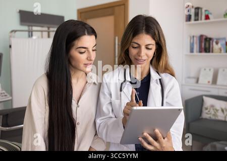 Positiver hispanischer Arzt zeigt der Frau Tablette Stockfoto
