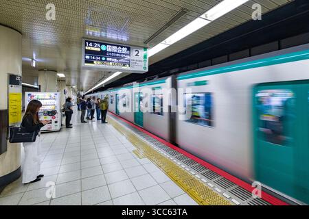 U-Bahnsteig mit Pendlern, wenn ein Zug ankommt. Die Menschen sind mit ihren Telefonen beschäftigt und warten auf die nächste Fahrt und zeigen urb Stockfoto