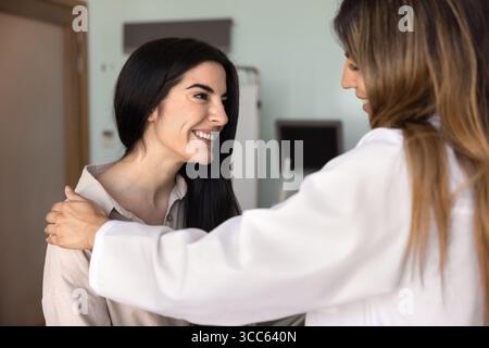Glückliche aufgeregte junge Lateinfrau, die einen Arzt besucht Stockfoto