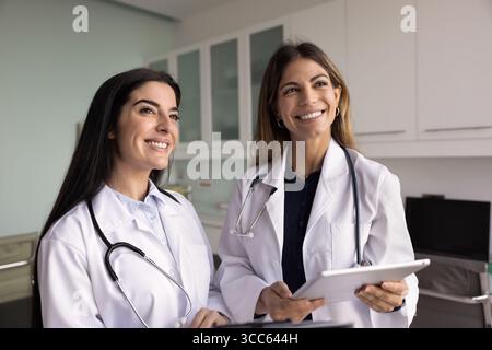 Zwei glückliche Ärztinnen stehen zusammen im Klinikzimmer Stockfoto