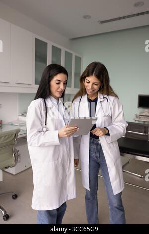 Positive Ärztinnen, die gemeinsam einen Tablet-Computer benutzen Stockfoto