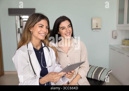 Glückliche Ärztin und fröhliche Patientin, die auf der Couch sitzt Stockfoto
