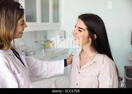 Positive lateinische Ärztin, die die Schulter einer Patientin berührt Stockfoto