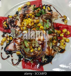 Salat mit Ziegenkäse, Tomaten, Thunfisch, Zwiebeln, süßem Mais mit Balsamico-Essig aus Modena Stockfoto
