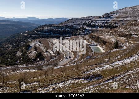 snowy mountain scenery crossed by a road with several vehicles on it Stockfoto