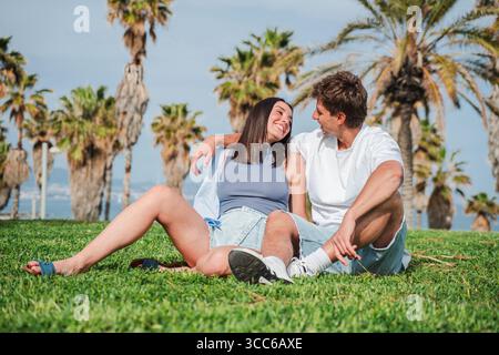 Fröhliche Paare, die an einem schönen, sonnigen Tag im Park zusammen sitzen und lachen. Hochwertige Fotos Stockfoto