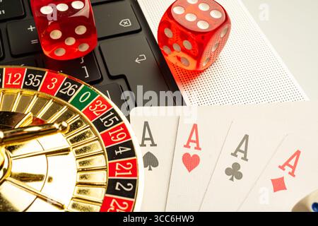 Das Bild zeigt eine Kombination aus Casino-Elementen, darunter Spielkarten-Pik, Würfelsäcke, Roulette-Rad und Laptop, die auf Online-Glücksspiel hinweisen Stockfoto