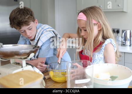 Mädchen, das Eier zum Backen von Kuchen in der Küchenschüssel mit dem Handrührer verquirlt Stockfoto