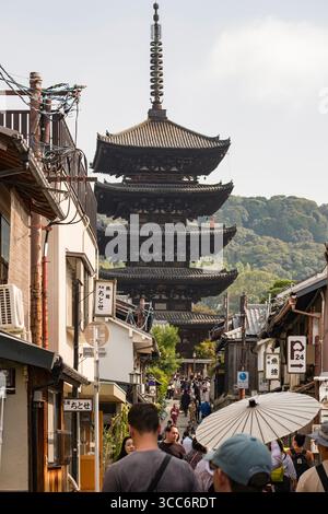 Überfüllte Straße in Kyoto voller Touristen und Einheimischer, die zu einer traditionellen japanischen Pagode führt. Die lebhafte Atmosphäre fängt das Wesen Japas ein Stockfoto