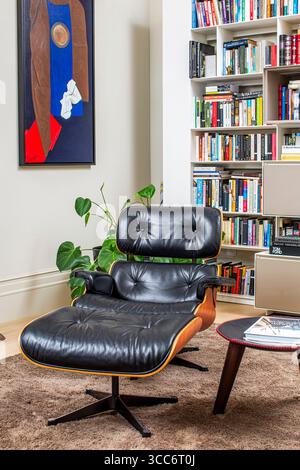 Ein Eames Lounge Chair mit poliertem schwarzem Leder, das in einem modernen Wohnzimmerkontext gestaltet ist. Stockfoto