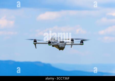 Drohne fliegt über Berge unter blauem Himmel mit Wolken Stockfoto