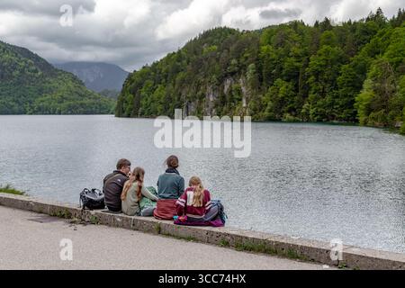 SCHWANGAU, DEUTSCHLAND - 23. MAI 2024: Unbekannte Jugendliche entspannten sich an einem bewölkten Frühlingstag auf dem Stadtdamm in der Nähe des Alpsees Stockfoto