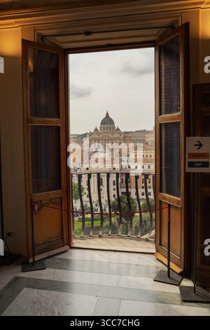 Blick von einem offenen Balkon auf das Engelsburg mit Blick auf die Dächer von Rom und den Petersdom in der Ferne. Stockfoto