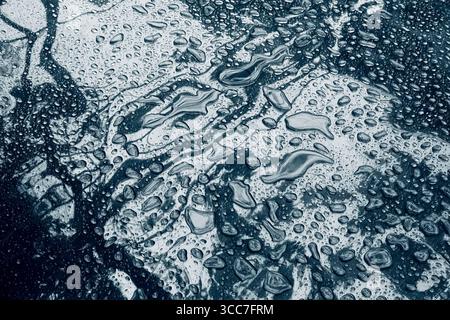 Wassertropfen unterschiedlicher Größe auf einer glänzenden Oberfläche. Nahaufnahme mit leichtem Ton Stockfoto