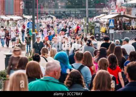 Überfüllte Straße, urbanes Leben, Stadtmenschen. Eine große Gruppe von Menschen, die an einem sonnigen Tag durch die geschäftige Innenstadt laufen, spiegelt die lebhafte Atmosphäre der Stadt und den Taucher wider Stockfoto