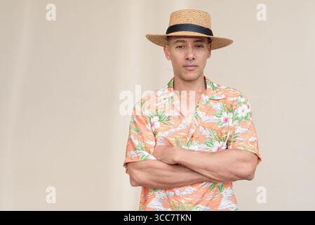 Glücklicher hispanischer Mann mit Panamahut und tropischem hawaiianischem Hemd, gekleidet in legere Sommermode. Der fröhliche Tourist posiert in entspanntem Urlaub Stockfoto