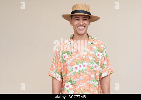 Glücklicher hispanischer Mann mit Panamahut und tropischem hawaiianischem Hemd, gekleidet in legere Sommermode. Der fröhliche Tourist posiert in entspanntem Urlaub Stockfoto
