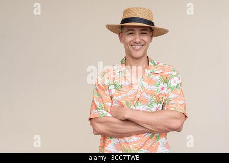 Glücklicher hispanischer Mann mit Panamahut und tropischem hawaiianischem Hemd, gekleidet in legere Sommermode. Der fröhliche Tourist posiert in entspanntem Urlaub Stockfoto