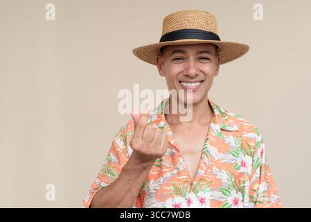 Glücklicher hispanischer Mann mit Panamahut und tropischem hawaiianischem Hemd, gekleidet in legere Sommermode. Der fröhliche Tourist posiert in entspanntem Urlaub Stockfoto
