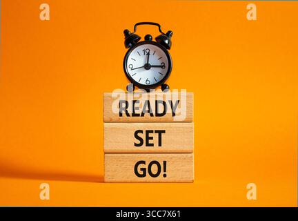 Symbol bereit Set Go. Concept Words Ready Set auf Holzblöcken. Schöner oranger Hintergrund mit Wecker. Business- und Ready-Go-Konzept. Cop Stockfoto