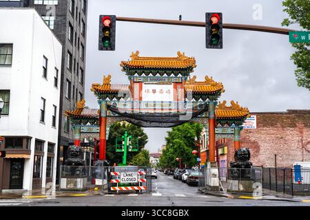 Portland, Oregon - 21. Juni 2025: Das Chinatown Friendship Gate am Eingang zum Viertel Old Town Chinatown an einem nassen, bewölkten Tag mit sichtbaren Bauschildern Stockfoto