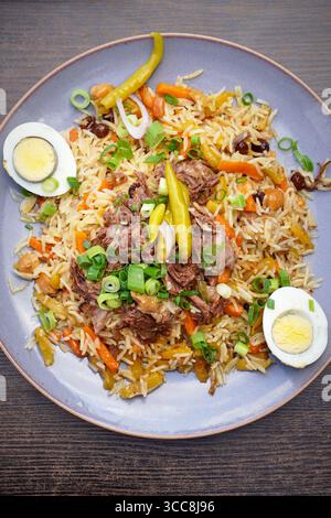 Servieren von Pilaw mit Fleisch, Kräutern und Gemüse garniert mit Zitrone Stockfoto